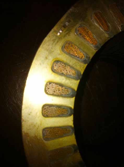 Cutaway of a winding showing conductors in the slots, slot liners, and top sticks, and an encapsulation varnish.
